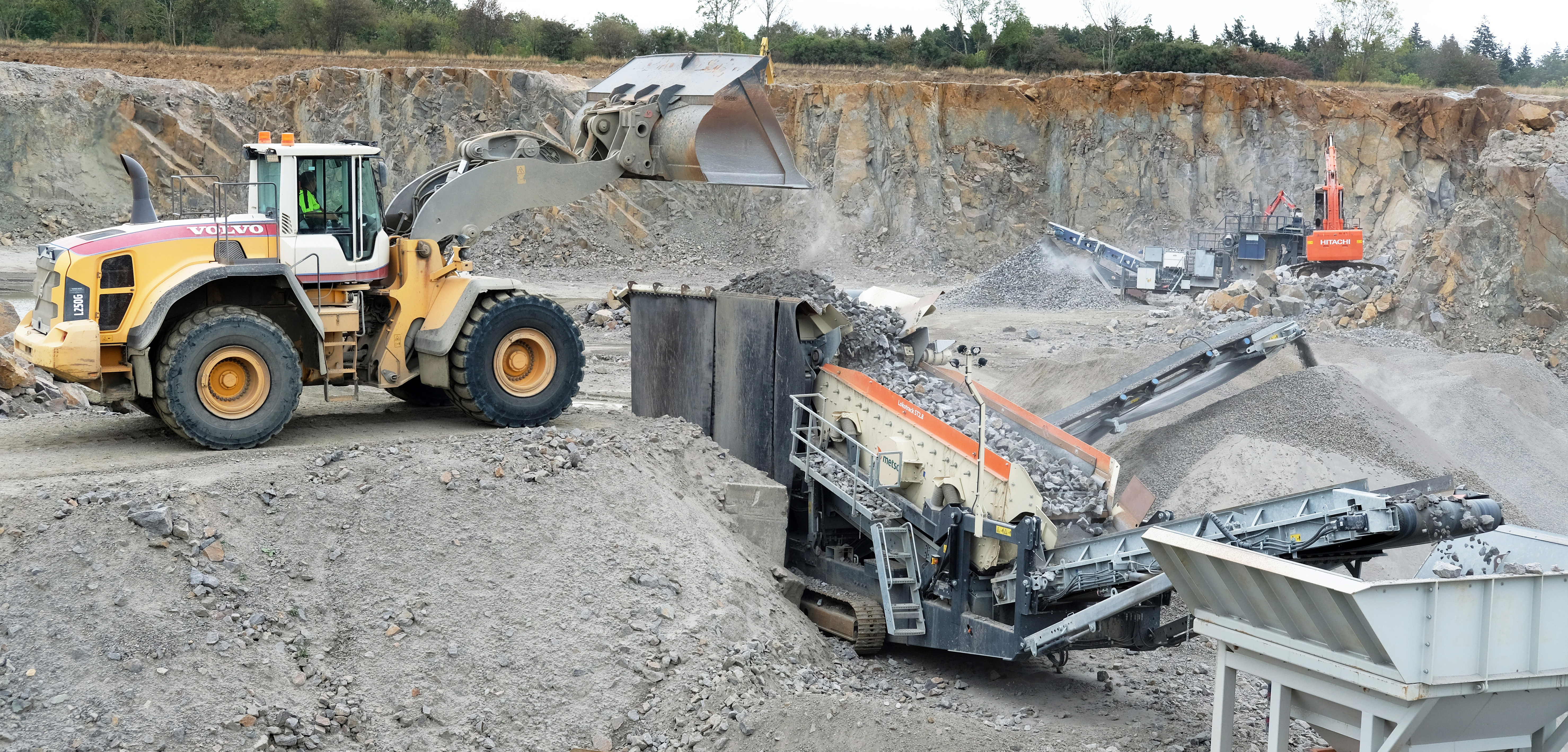 An excavator feeding a Lokotrack at a quarry.