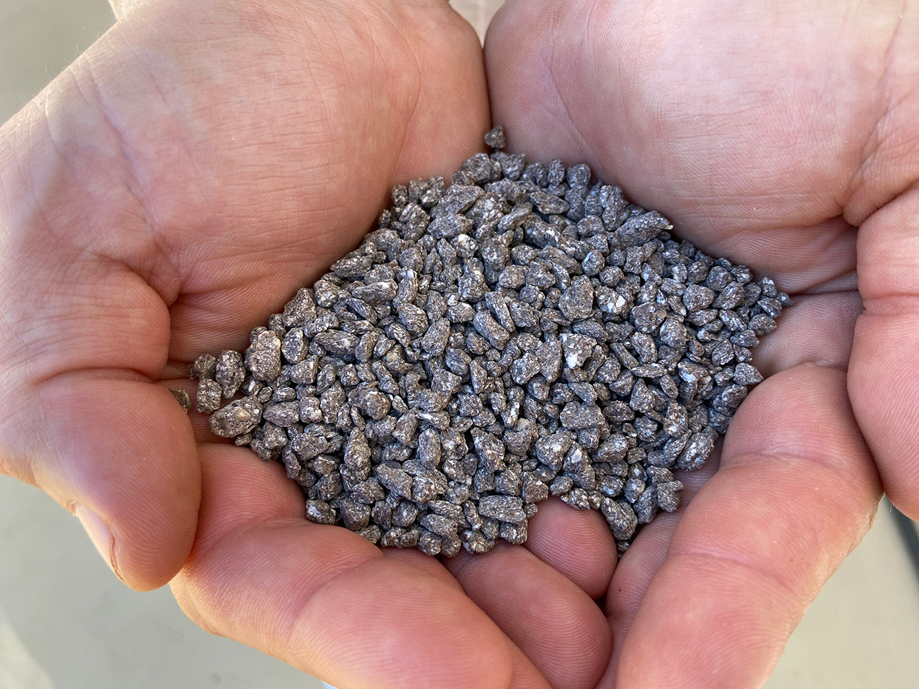 A scoop of fertilizers pictured in hands.