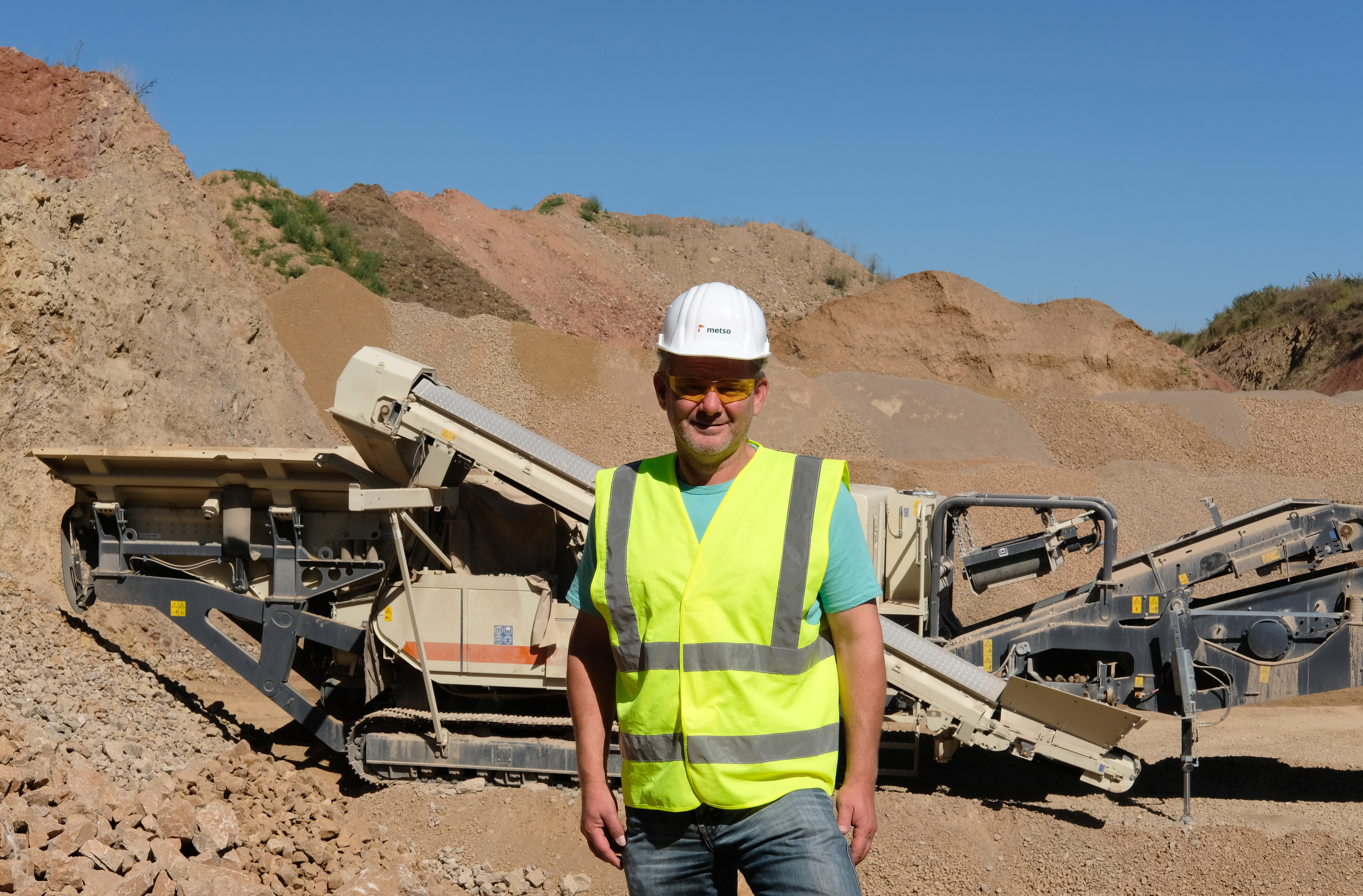 A man standing at a quarry with a Lokotrack in the background.