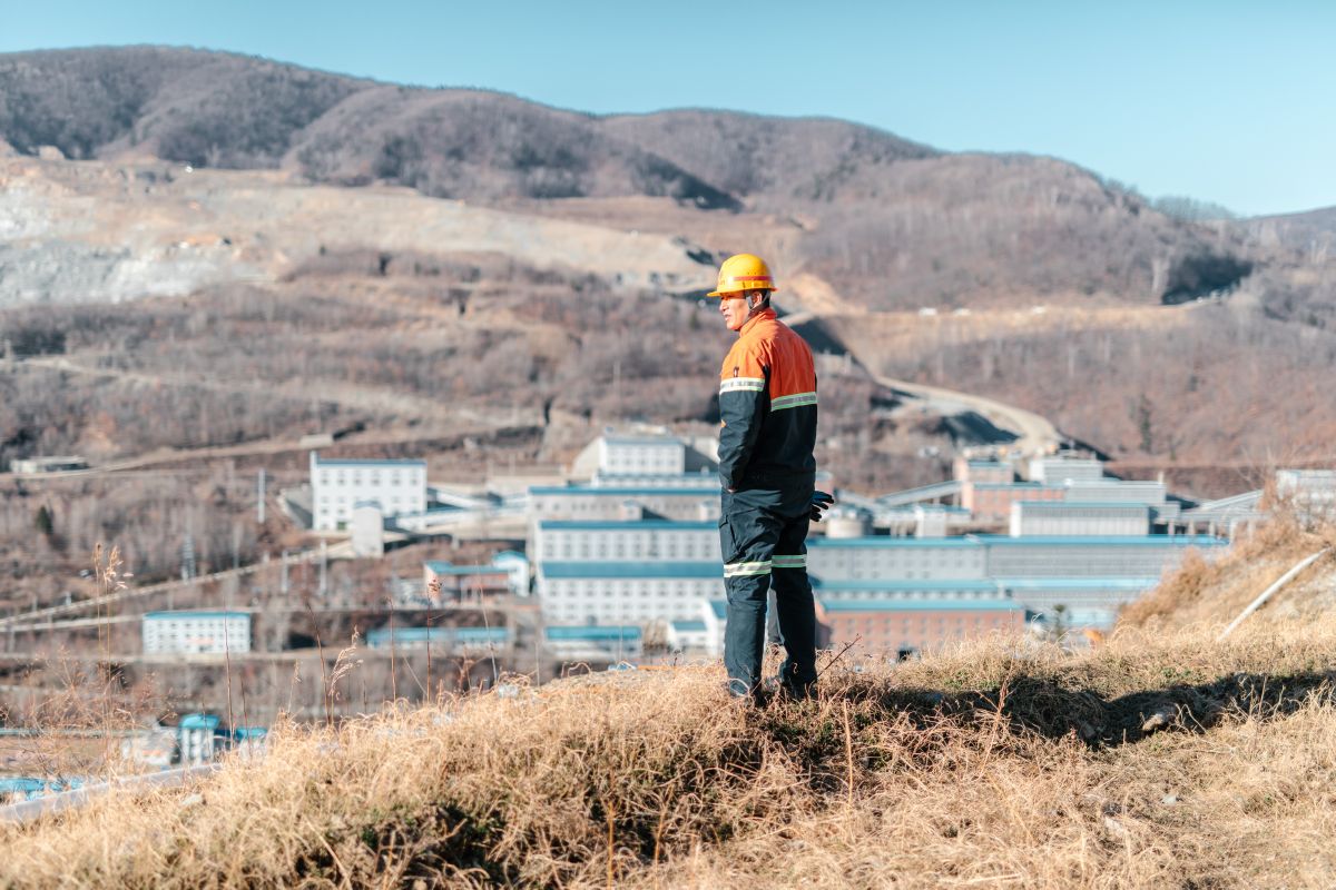 Man looking down from a small hill, down to the Hunchun Zijin mining site.