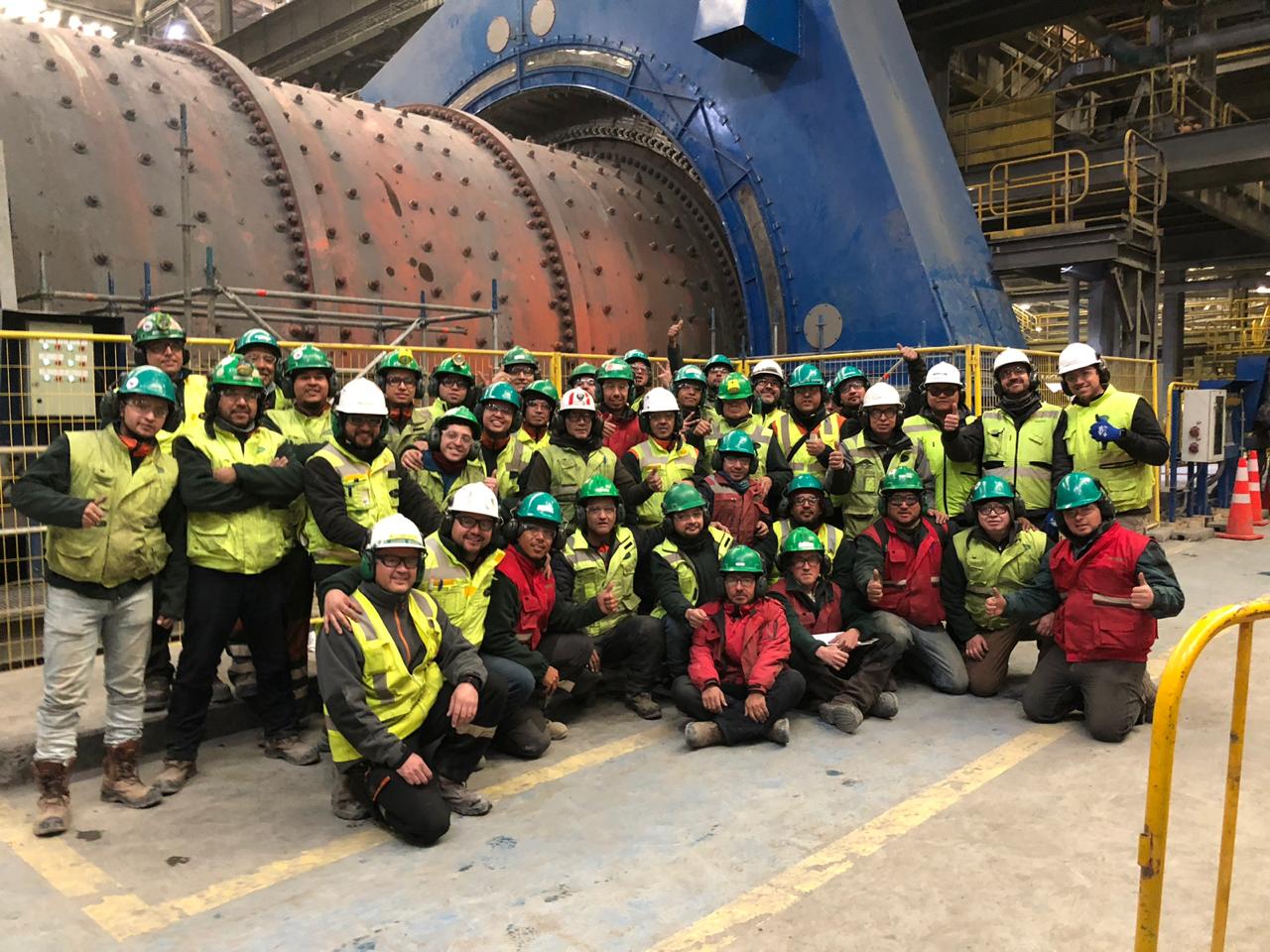 Team of maintenance employees pictured in front of a ball mill at Collahuasi mine.