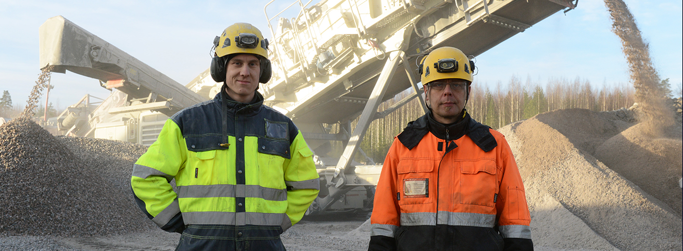 Two men posing for the camera in safety gear with Lokotrack LT330D in the background.