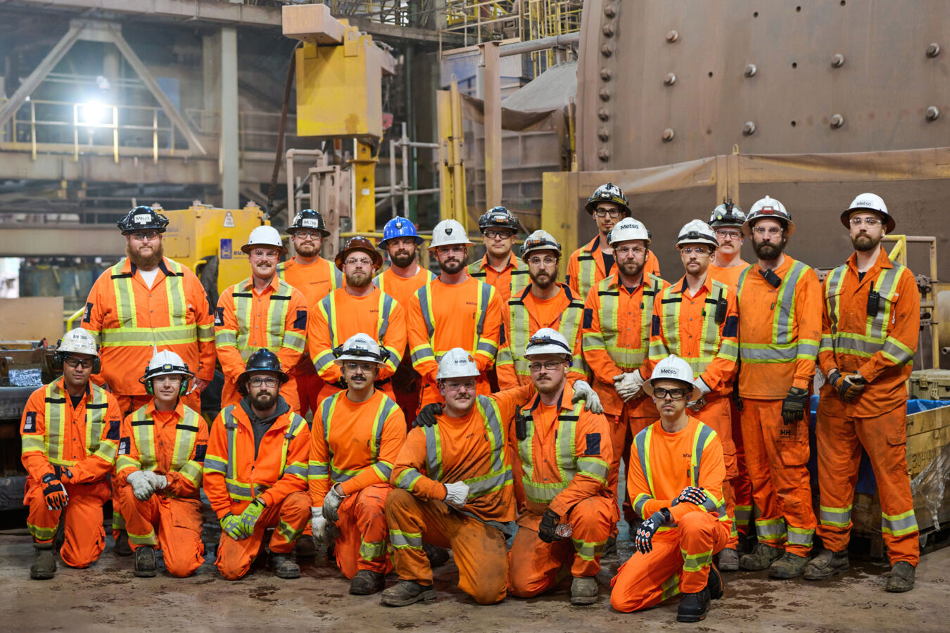 Group of Metso reline employees in PPE standing together in from of a grinding mill