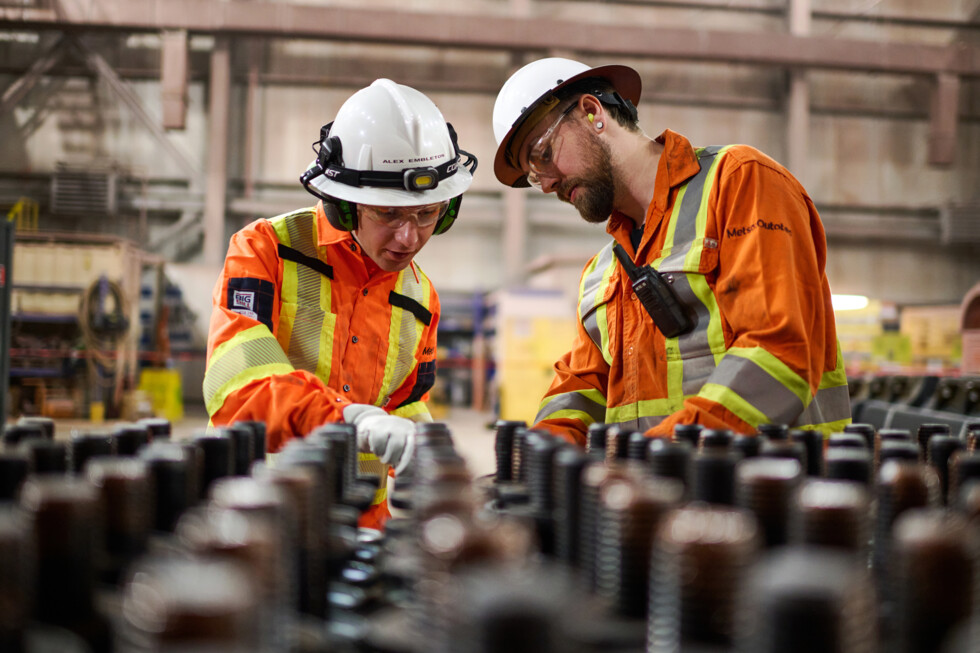 Two Metso workers in PPE looking at a row of bolts